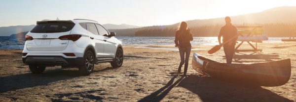 The 2018 Hyundai Santa Fe Sport at the beach, with a couple and a canoe nearby.